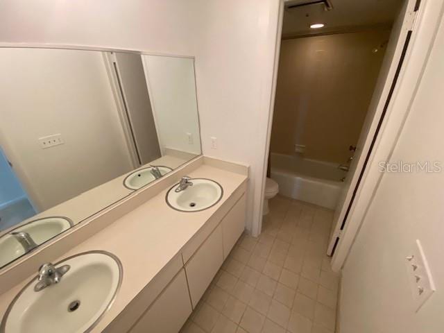 bathroom with a tub to relax in, a sink, toilet, and double vanity