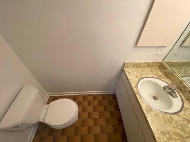 half bath with toilet, vanity, and baseboards