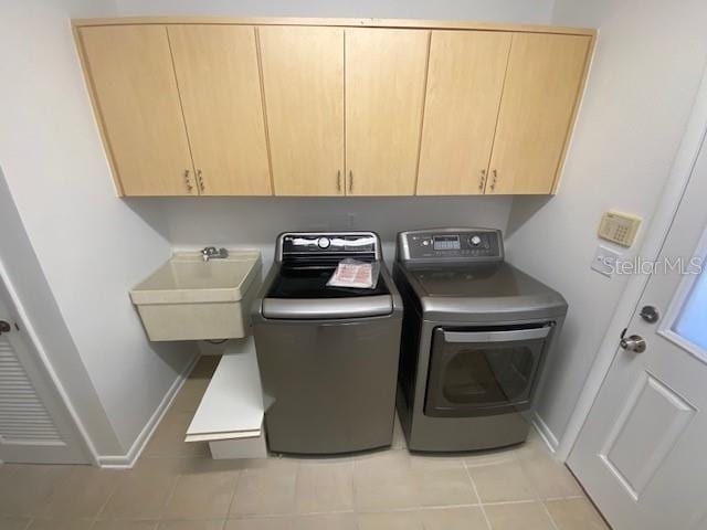 washroom with cabinet space, a sink, washer and clothes dryer, and baseboards