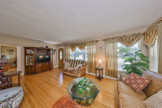 living room with baseboards, visible vents, light wood finished floors, and a textured ceiling