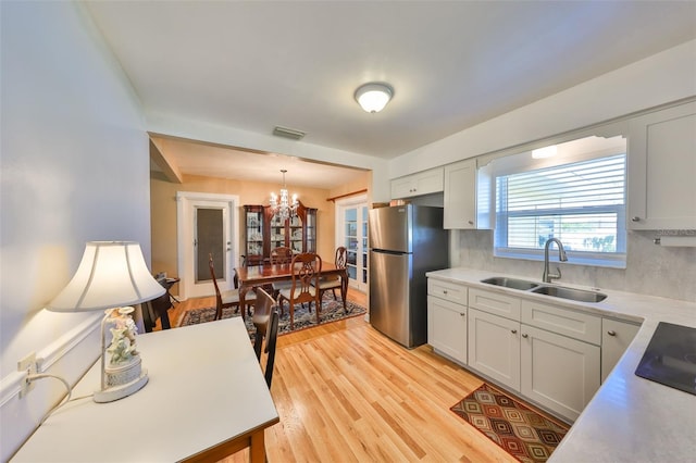 kitchen with visible vents, freestanding refrigerator, light countertops, light wood-style floors, and a sink