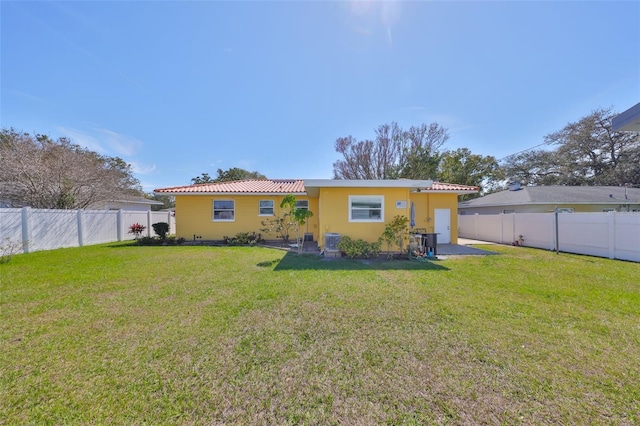 back of house with a fenced backyard, central AC, and a yard