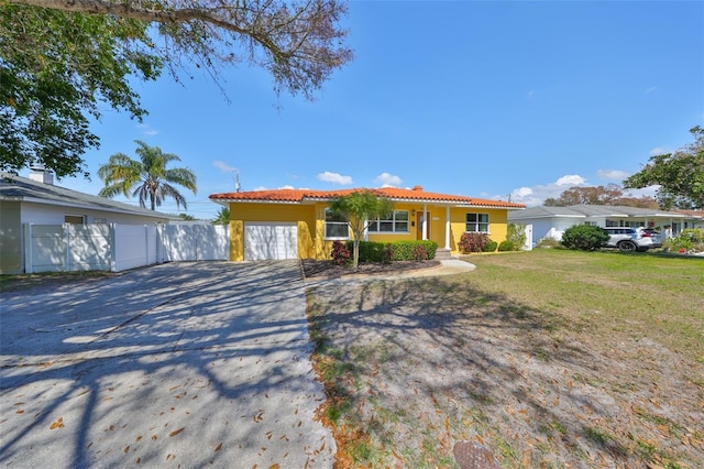 view of front of home featuring a tile roof, fence, concrete driveway, stucco siding, and a front lawn