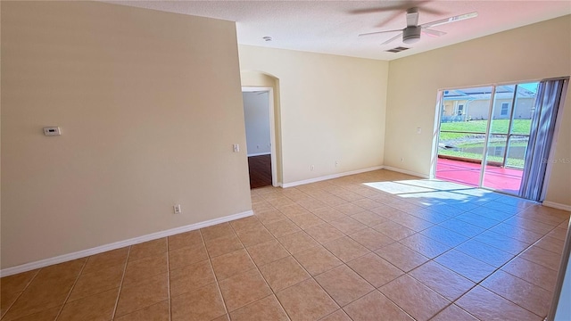 spare room featuring light tile patterned floors, baseboards, arched walkways, visible vents, and ceiling fan