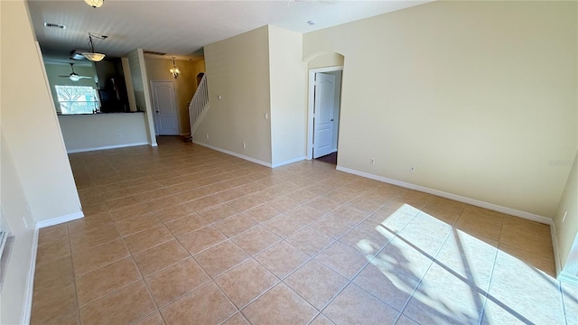 spare room featuring arched walkways, baseboards, and light tile patterned floors