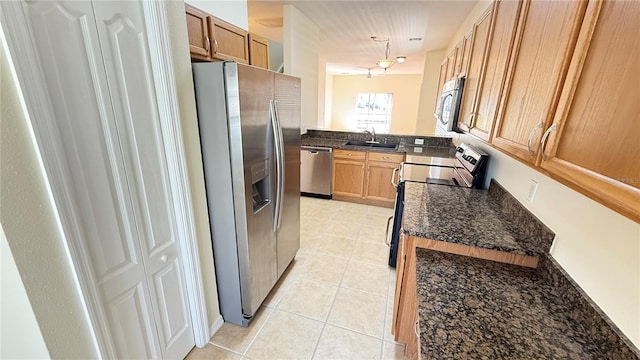 kitchen featuring light tile patterned flooring, dark stone countertops, a sink, and stainless steel appliances