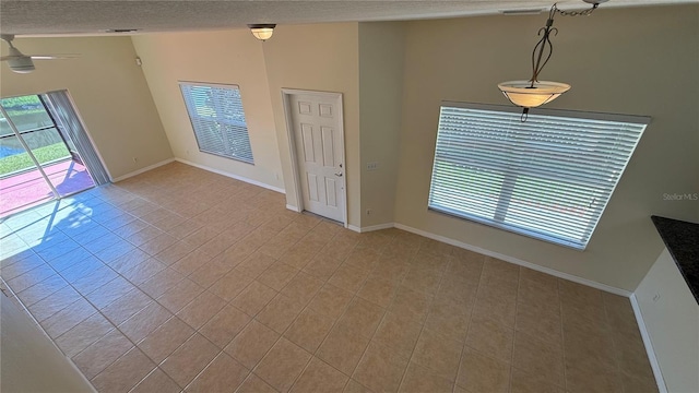 interior space with a wealth of natural light, light tile patterned floors, baseboards, and a textured ceiling