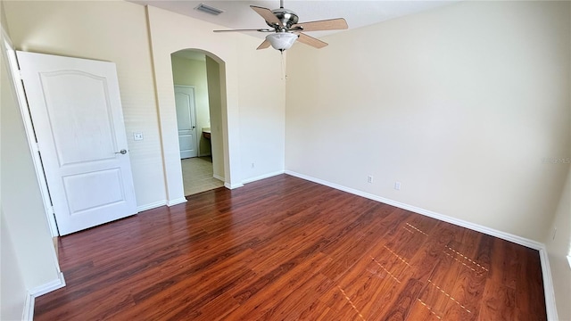 empty room with a ceiling fan, wood finished floors, baseboards, visible vents, and arched walkways