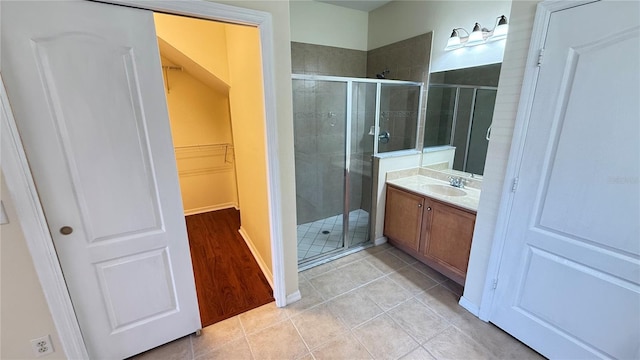 bathroom with tile patterned floors, vanity, a walk in closet, and a shower stall