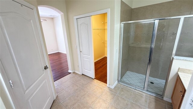 full bathroom featuring tile patterned flooring, baseboards, vanity, a stall shower, and a spacious closet