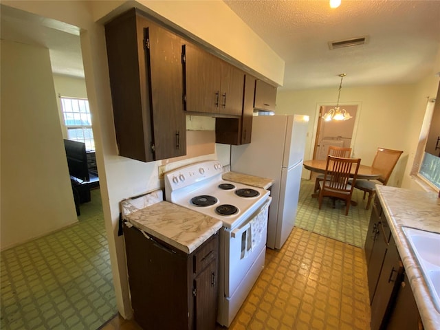 kitchen with white range with electric stovetop, light floors, light countertops, visible vents, and an inviting chandelier