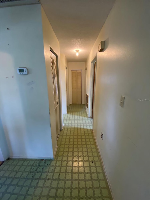 hall with baseboards and a textured ceiling