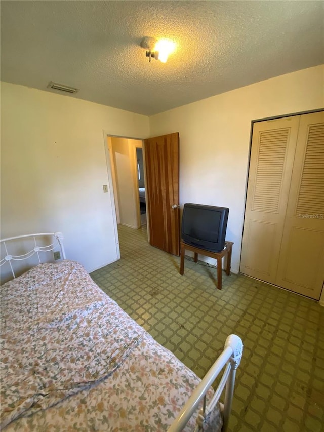 bedroom featuring a closet, visible vents, a textured ceiling, and tile patterned floors