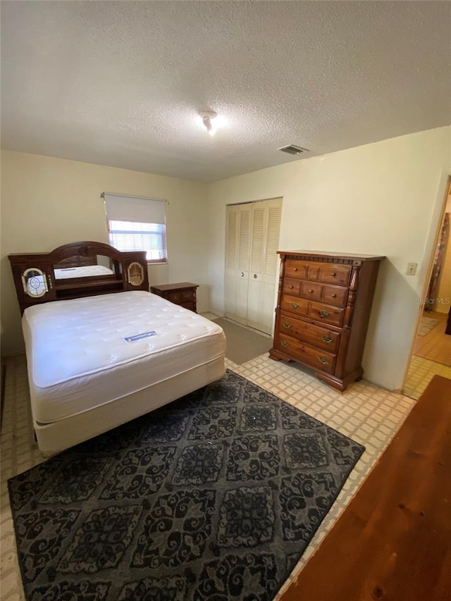 bedroom featuring light floors, visible vents, and a textured ceiling