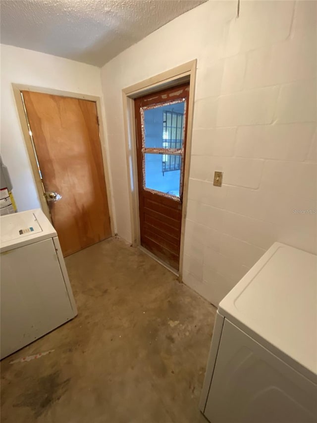 interior space with concrete block wall, laundry area, and washer / clothes dryer