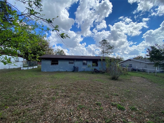 rear view of property featuring central AC unit, fence, and a yard