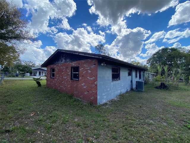 view of property exterior featuring cooling unit, concrete block siding, a lawn, and fence