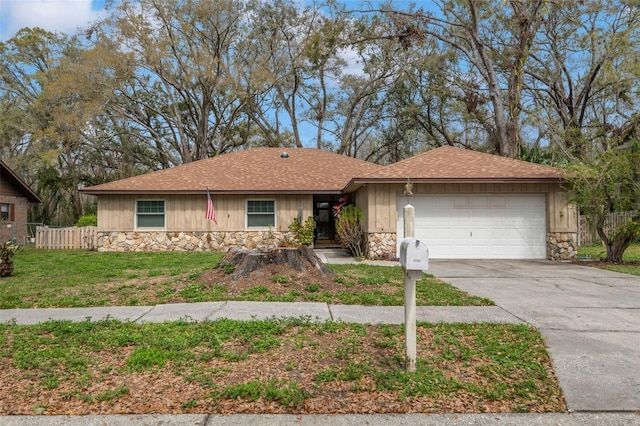 ranch-style home featuring an attached garage, fence, stone siding, driveway, and a front lawn