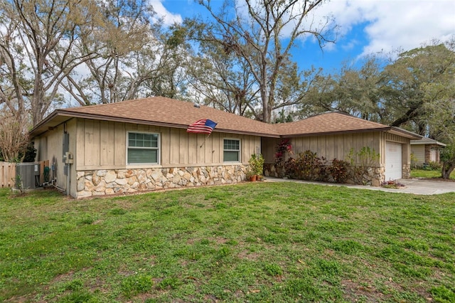 ranch-style home with a garage, stone siding, and a front lawn