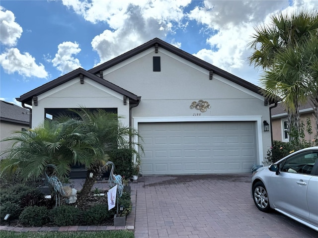 single story home with a garage, decorative driveway, and stucco siding