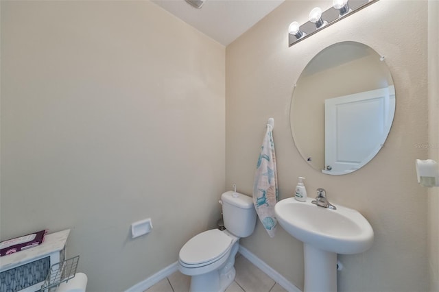 half bathroom with baseboards, toilet, and tile patterned floors