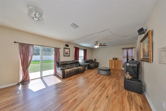 living room with light wood finished floors, a ceiling fan, visible vents, and baseboards