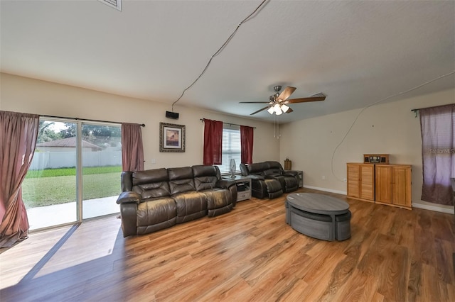 living area with light wood-style floors, baseboards, and a ceiling fan