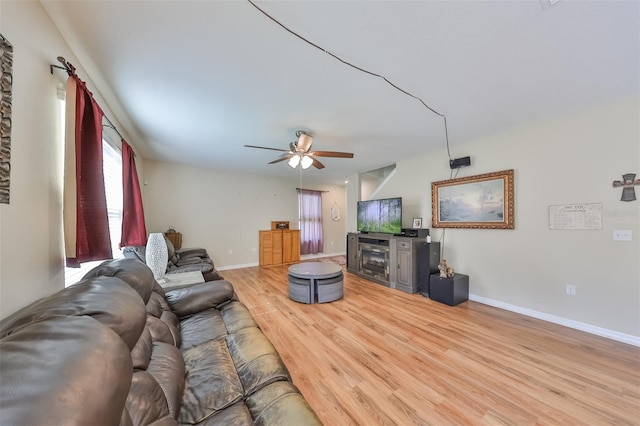 living area with baseboards, a ceiling fan, and light wood-style floors