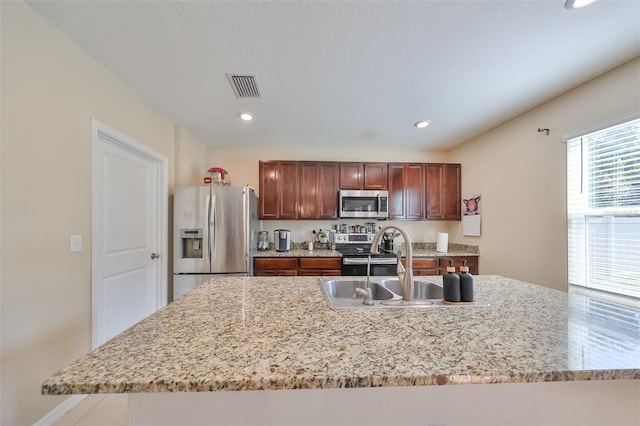 kitchen featuring recessed lighting, stainless steel appliances, a sink, visible vents, and an island with sink