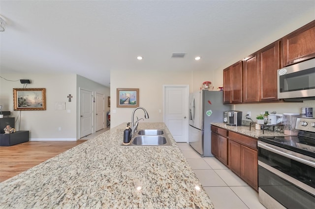 kitchen featuring stainless steel appliances, recessed lighting, visible vents, a sink, and light stone countertops