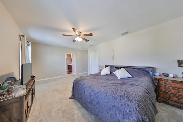 bedroom featuring light carpet, baseboards, visible vents, a ceiling fan, and ensuite bath