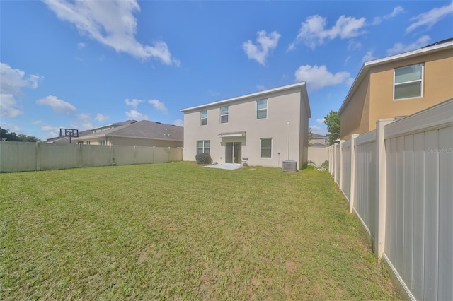 rear view of house with a fenced backyard, a lawn, central AC, and stucco siding