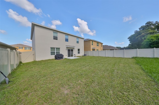 rear view of property featuring a fenced backyard, a gate, a lawn, and stucco siding