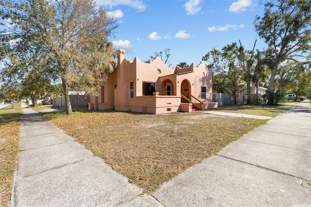 adobe home featuring a front yard, fence, and stucco siding