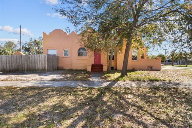 view of front of house featuring entry steps, crawl space, fence, and stucco siding