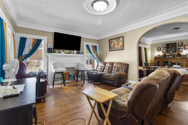 living area with arched walkways, a fireplace, crown molding, and a textured ceiling