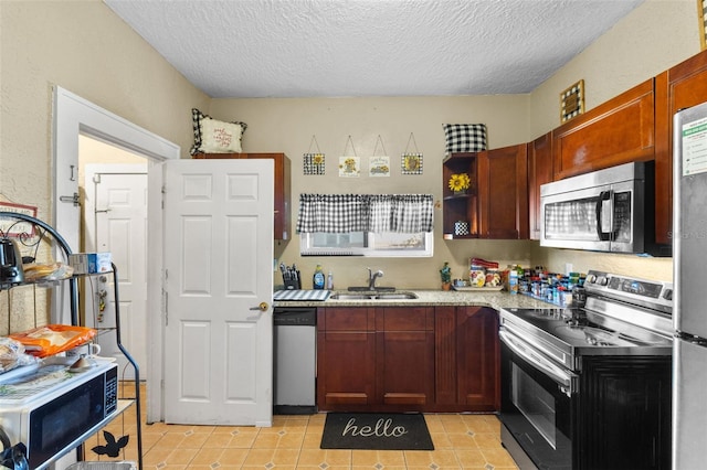 kitchen with light tile patterned floors, a textured ceiling, stainless steel appliances, and a sink