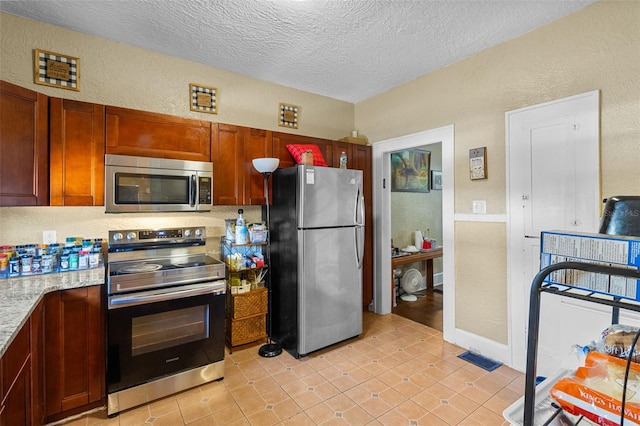 kitchen featuring stainless steel appliances, a textured ceiling, and a textured wall