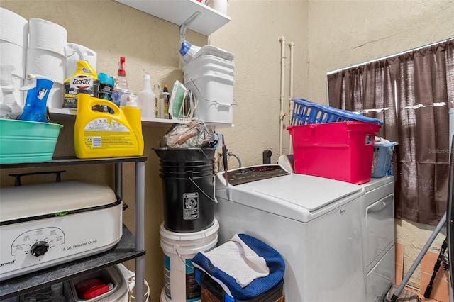 washroom featuring a textured wall, laundry area, and separate washer and dryer