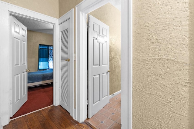 corridor with a textured wall and wood finished floors