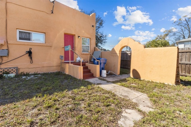 view of side of home with a fenced front yard and stucco siding