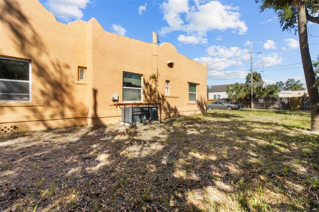 back of house with fence, cooling unit, and stucco siding