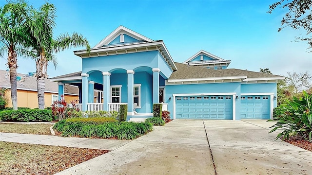 view of front of home with a garage, concrete driveway, covered porch, and stucco siding