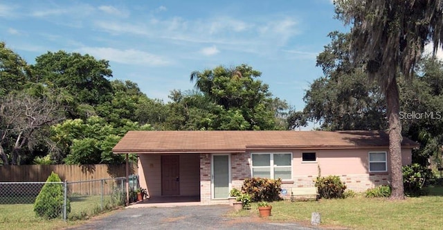 ranch-style home with a front yard, fence, aphalt driveway, and brick siding