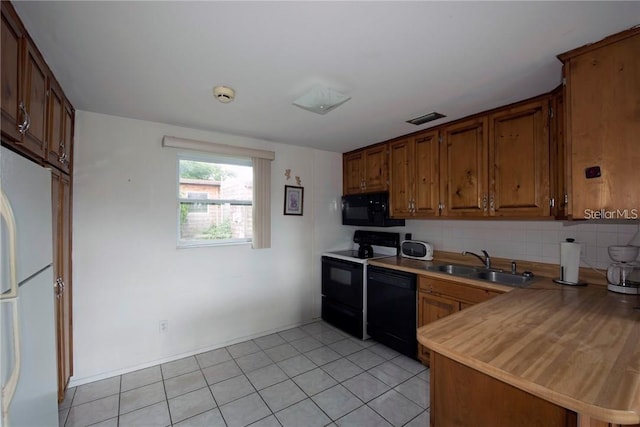 kitchen with brown cabinets, tasteful backsplash, light countertops, a sink, and black appliances