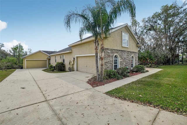 view of front of home with concrete driveway, stone siding, an attached garage, a front lawn, and stucco siding