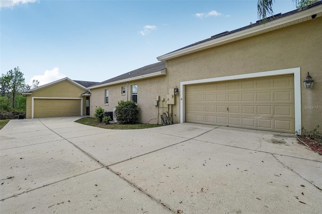 ranch-style house with driveway, an attached garage, and stucco siding