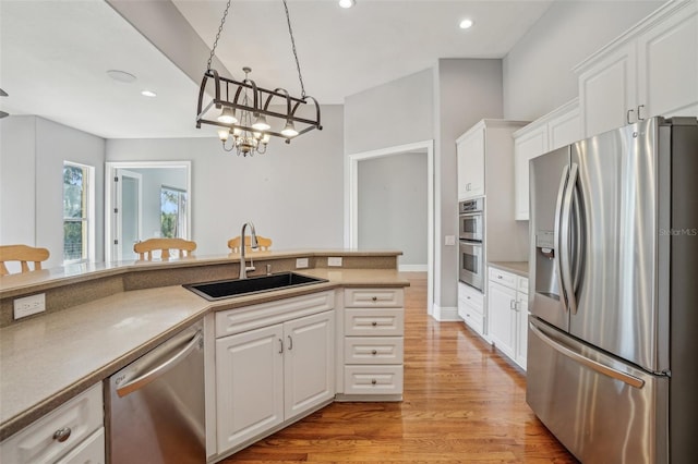 kitchen featuring light wood finished floors, stainless steel appliances, recessed lighting, white cabinets, and a sink