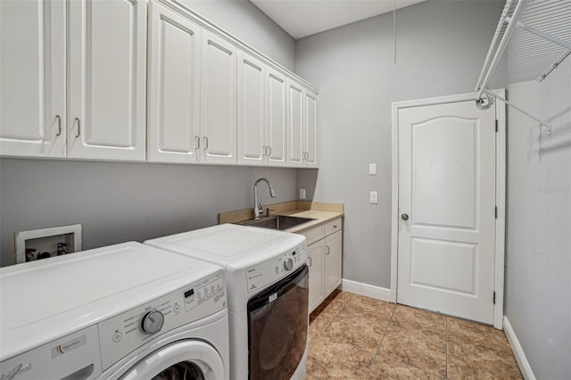 washroom featuring cabinet space, a sink, baseboards, and separate washer and dryer