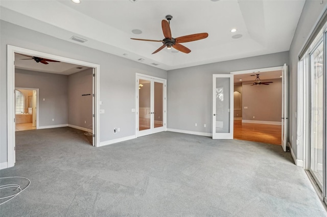 unfurnished bedroom with a tray ceiling, french doors, carpet flooring, and baseboards